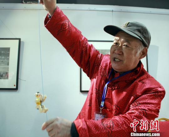 圖為劉志斌展示“娃娃攀繩”木偶?！∮诳×痢z