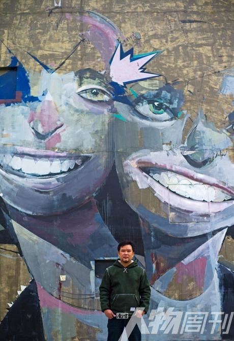 　　杨福徐站在大芬村街头不知名作者的涂鸦前。最惨的时候，他一年只有三四万的收入，现在他的原创作品已经被人接受，走出了困境 图/本刊记者 大食