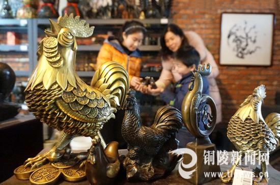 2017年1月22日，在铜街一家铜工艺品店铺里，铜陵市民在欣赏选购“铜鸡”工艺品。