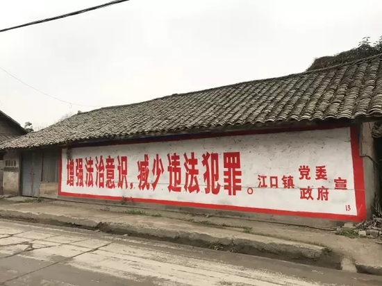 江口镇一处民房粉刷着一行标语,“增强法治意识,减少违法犯罪。”