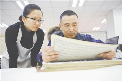 刘建明正在指导徒弟装帧古籍。