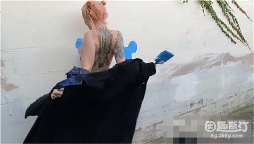 从影片中，可以看到身材曼妙的女子脱下大衣后，露出诱人的身材曲线，将涂满蓝漆的身体贴在墙面磨蹭，在墙上留下专属的街头涂鸦。