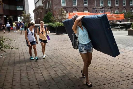 Emma Sulkowicz，哥伦比亚大学视觉艺术学生扛着一个床垫表示学校对于自己在2年级的时候被性侵的事件视而不见的态度的抗议，2014年9月5日。图片：致谢Andrew Burton/Getty Images