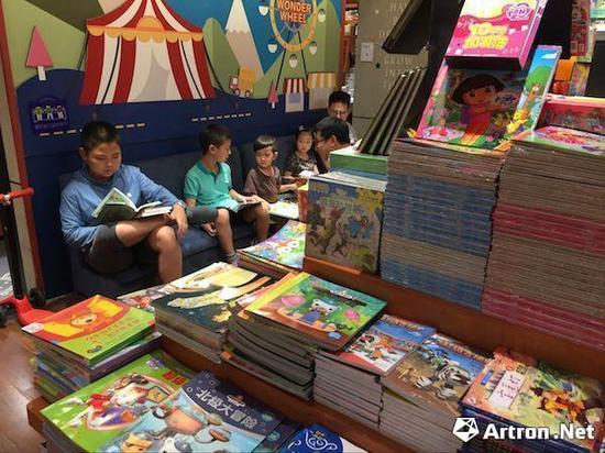 在西西弗书店内专门设置的绘本区域，家长陪同小孩在选择、阅读绘本书籍