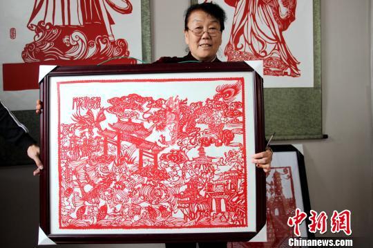 图为赵文花展示其剪纸作品《鲤鱼跃龙门》。　阿琳娜 摄