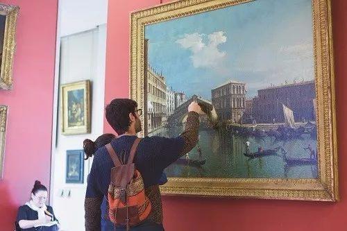 卢浮宫的一名游客被Canaletto于18世纪的画作《The Rialto Bridge in Venice》深深吸引住。