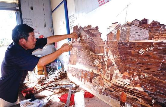 陈立强正在制作老郧阳西河码头树皮粘贴画。