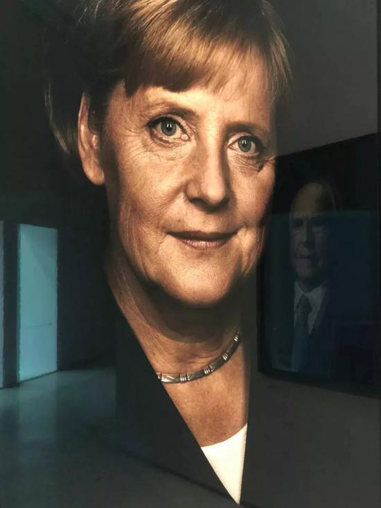 安德里亚斯·穆埃展览现场中的默克尔肖像，镜面反射的是科尔的肖像