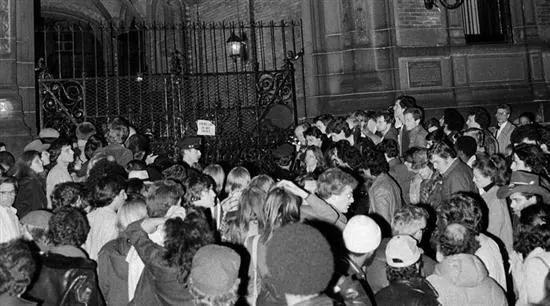 公寓前人群聚集，歌迷听到列侬遇害的消息后纷纷赶到了他的公寓楼下。