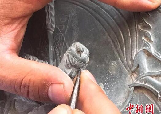 图为马万荣将原本冰凉普通的洮河绿石雕刻成栩栩如生的山水人物图案。