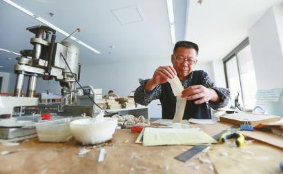 夏天妮在平装书上面垫层塑料膜后再修复 3日上午,山东师范大学长清校区,王斌整理破损的书页。 本版照片均由记者刘玉乐 摄