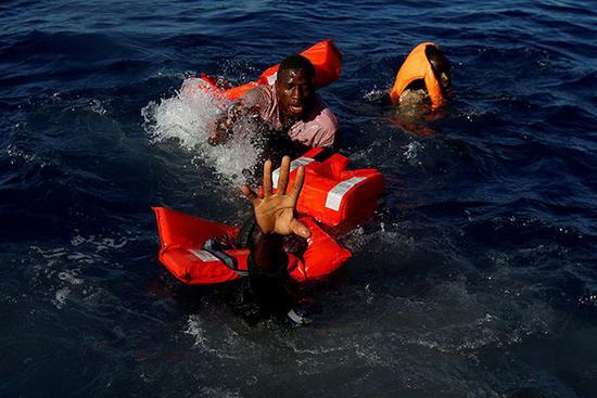 当地时间2017年4月14日，马耳他非政府组织在地中海救援一批移民，这些移民在乘坐的船倾覆后，努力地浮在水面上。