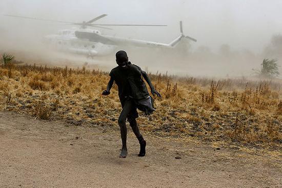 当地时间2017年2月18日，南苏丹北部Rubkuai，一名男孩在世界粮食计划署直升机着陆时跑开。