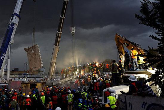 当地时间2017年9月20日，墨西哥墨西哥城，一座大楼在地震中坍塌，救援工人和士兵在现场进行搜救工作。