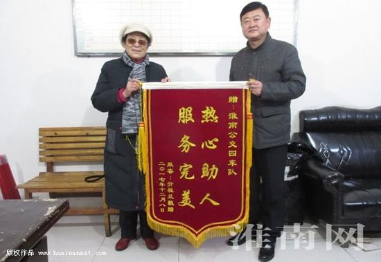 图:老人向车队送上锦旗表感谢
