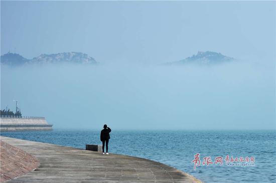 青岛日报/青岛观/青报网讯 3月26日，岛城沿海出现平流雾，摄影师用相机记录崂山在海上时隐时现的大美景观。