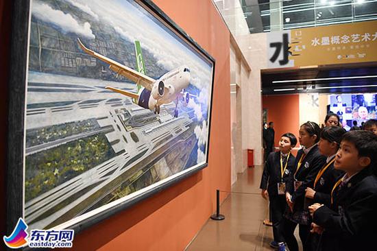 图片说明：在“水墨概念艺术大展”上，一群小观众正在欣赏作品《大飞机》。