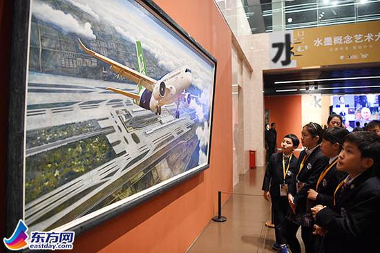 图片说明:在“水墨概念艺术大展”上,一群小观众正在欣赏作品《大飞机》。