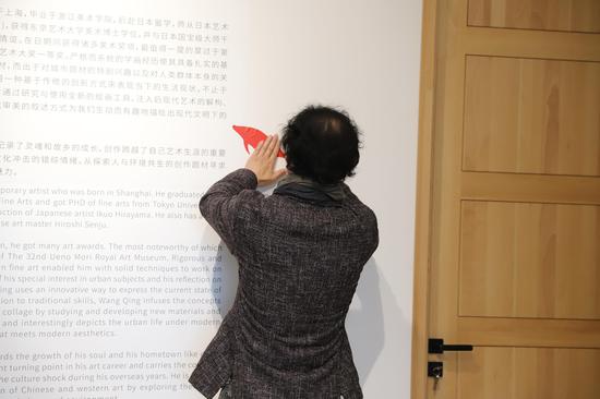 艺术家王青将小红鱼贴到墙上