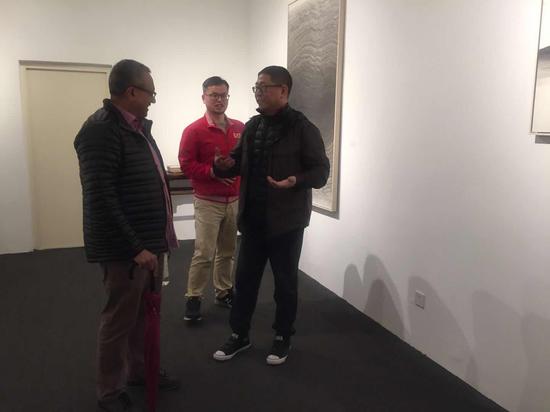 张朝晖（右）在开幕现场与观展艺术家交谈。