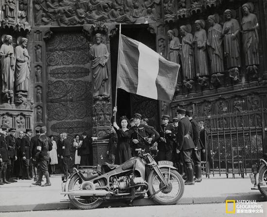 1944年8月26日，解放巴黎的军队在游行到巴黎圣母院时，一名法国女家庭教师挥动着三色旗表达敬意。供图：美国陆军通讯部