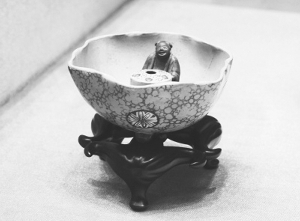 清代光绪绿地粉彩“公道杯”。“公道杯”为荷叶状,内以宜兴紫砂为胎,外施粉彩绿釉。杯内有一个怀抱圆柱的紫砂仙人,圆柱顶端有5个红点,分别指向在座饮酒之人,用来行酒令。之所以叫“公道”,奥妙在于中空的圆柱之内:酒倒入杯中后,紫砂仙人会慢慢上升,如果升到一定高度还继续斟酒,就会被视为有失公允,倒入的酒会通过“虹吸现象”一滴不剩地全部流出