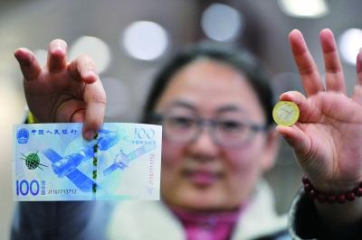 工行东城支行营业厅的工作人员展示新发行的航天纪念钞、纪念币 摄 记者 林晖