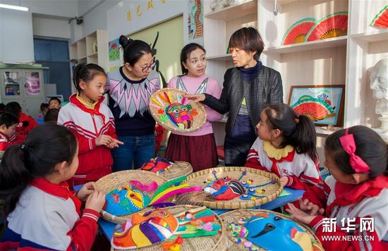 12月17日，内蒙古呼和浩特市玉泉区通顺街小学的老师和喜欢面具艺术的孩子一起交流面具绘制的技艺。