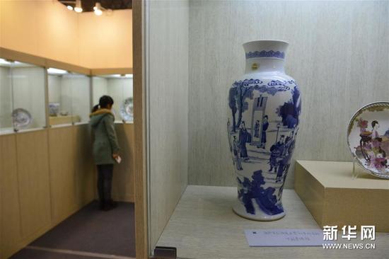 12月20日,一位观众在参观外销瓷展览,右侧是康熙青花“版筑求贤”故事观音瓶。