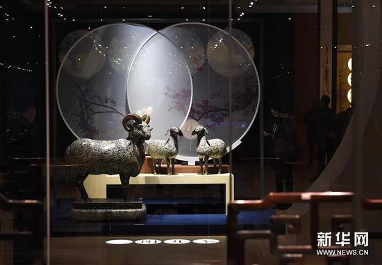 12月25日，观众在“三阳开泰”展位上陈列的文物旁参观。