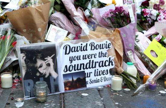 这是1月12日在英国伦敦南部布里克斯顿一面画着大卫·鲍伊著名肖像的墙前拍摄的鲜花和悼念卡片。新华社记者韩岩摄 
