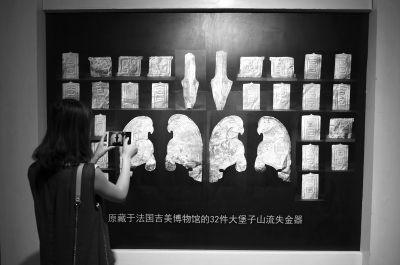 7月20日，在甘肃省博物馆，一位观众拍摄法国无偿归还我国的32件流失文物的展览图。新华社发