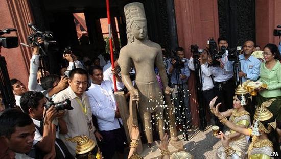 游客们在雕像的臂膀上挂上白色的花环，身着金色服装的表演者向雕塑丢失的足部抛撒花瓣。（图片来源：经济学人）