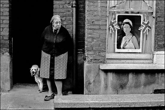 英国，英格兰，伦敦。 女王钻石禧年期间，一位年老的女人和狗站在家门口，前窗上挂着女王肖像和英国米字旗 伊恩·贝瑞