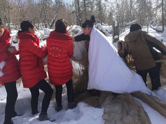 艺术家孔宁在工作人员的协助下准备在雪地里“洗澡”（图片：郭柏林）