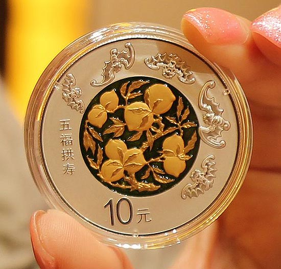 工作人员向媒体展示2016吉祥文化“五福拱寿”30克纪念银币