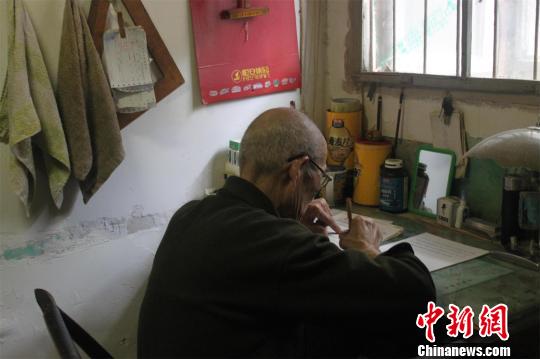 82岁的丁昌业戴着老花镜，正在伏案修改自己写就的《回忆录》初稿　梁婷　摄