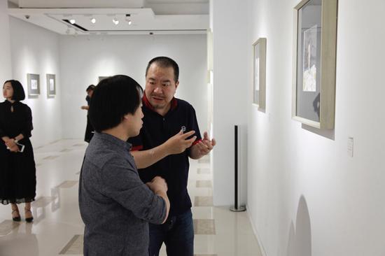 艺术家冯建宇（左）与鲁迅美术学院美术馆馆长王易罡（右）在展览现场交流