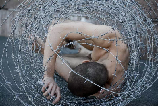 ▲ 2013年3月，彼得·帕弗伦斯基将自己赤身置于带刺钩的钢丝网中。摄影：Reuters