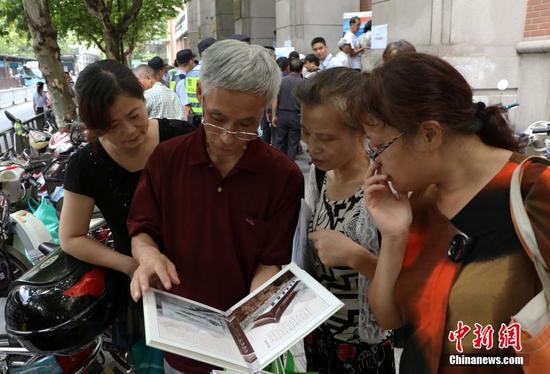 几位杭州市民欣赏已买到的“G20杭州峰会明信片”。 中新社记者 王刚 摄