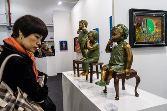 2015年11月13日,一名游客在上海艺术博览会上欣赏艺术品。(图片来源 视觉中国)