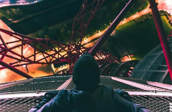 一位楼顶摄影师正趴在伦敦奥林匹克体育场的安赛乐米塔尔轨道边缘凝望下面的街景