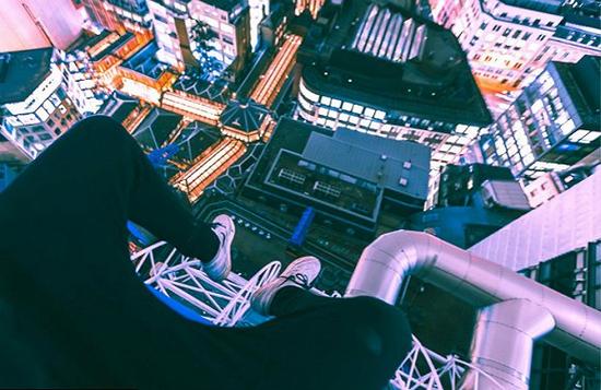 Lukas Spencer正坐在伦敦一座高楼大厦顶层的边缘，这张照片也是他的摄影系列作品之一