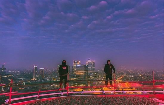 两位顶楼摄影师站在顶楼的边缘俯瞰伦敦金丝雀码头