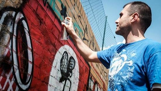 Ibo Omari在柏林创作一幅基于纳粹十字的涂鸦作品。图片来源：Deutsche Presse-Agentur