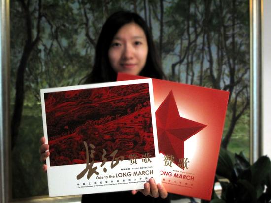 工作人員展示《長征贊歌》中國工農紅軍長征勝利八十周年郵票珍藏