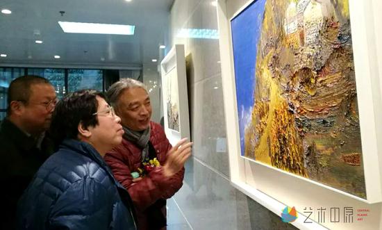 易英先生、化建国先生在展览现场认真观看孟新宇的作品《红高粱》
