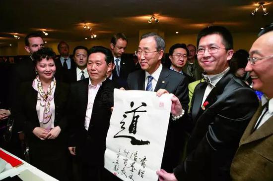 2007年3月,吴欢在联合国总部举办“吴氏家族中国书画展”,联合国秘书长潘基文亲临开幕式并致辞。图为潘基文(中)接受吴欢(左二)赠送的书法作品“道”