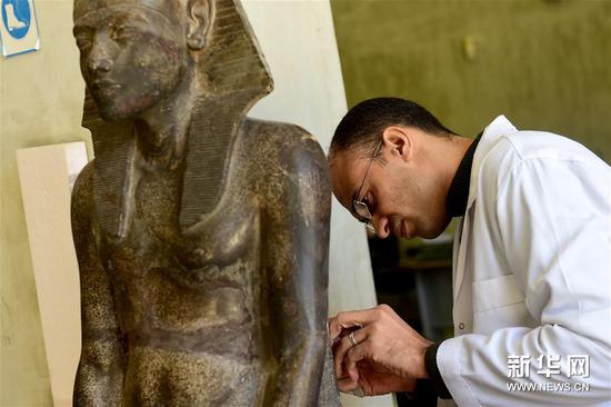 埃及开罗，一名专家在大埃及博物馆内修复石像