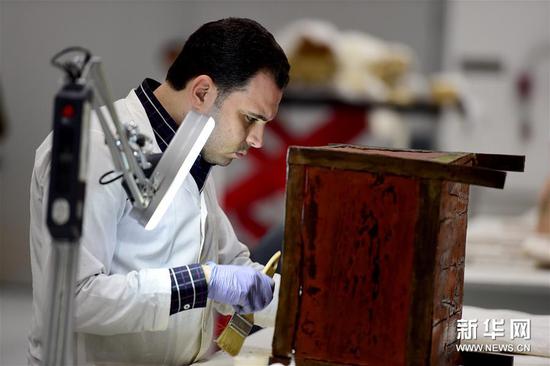 一名专家在大埃及博物馆木制品研究室内修复木箱